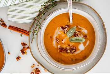 vegan pumpkin soup in a bowl with cinnamon sticks